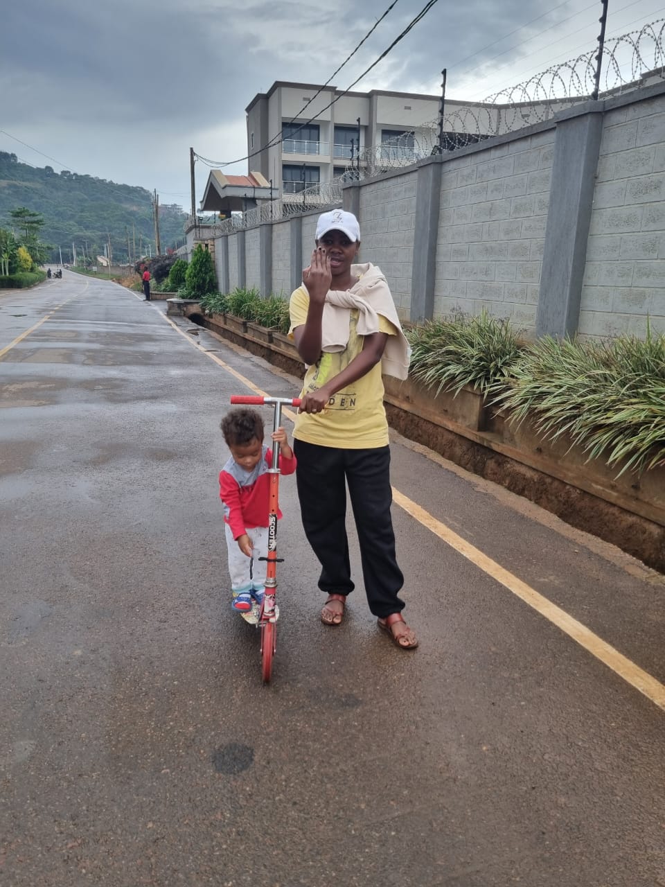Woman and child with scooter on a wet road.